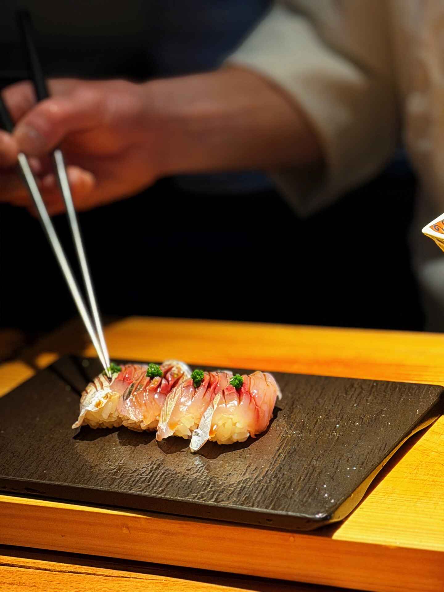 Finishing delicate pieces of sushi with herbs at the counter